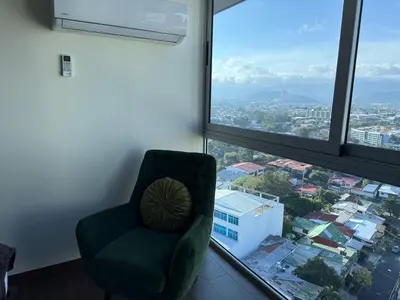 a green chair sitting in front of a large window at Penthouse San José Costa Rica in San José