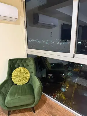 a green chair with a yellow pillow in front of a window at Penthouse San José Costa Rica in San José