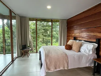 a bedroom with a bed with wooden walls and windows at Monte y Alma Monteverde in Cebadilla