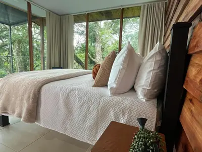 a bedroom with a bed with white pillows and a window at Monte y Alma Monteverde in Cebadilla