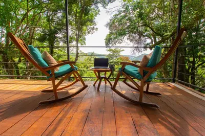 two chairs and a table on a wooden deck at Monte y Alma Monteverde in Cebadilla