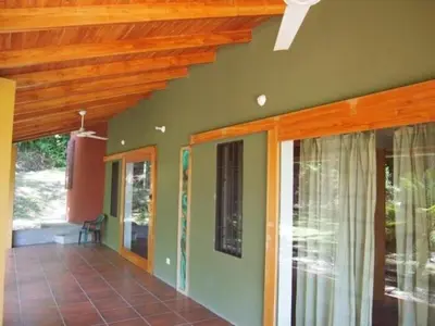 a porch of a house with green walls and wooden ceilings at Casa Redonda Tranquil House 15 Minutes from Samara by Car in Nicoya