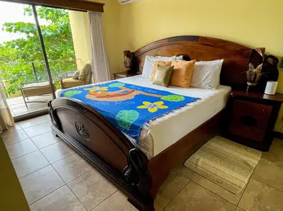 a bedroom with a large bed with a blue blanket at Beachfront Terrace Sunset 3B in Jacó
