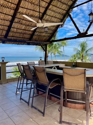 a patio with a table and chairs and the ocean at Beachfront Terrace Sunset 3B in Jacó