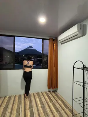 a woman standing in a room looking out the window at SUA Luxury Arenal Volcano View Apartments in Fortuna