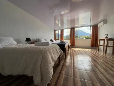 a bedroom with two beds and a large window at SUA Luxury Arenal Volcano View Apartments in Fortuna
