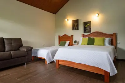 a bedroom with two beds and a couch at Cabañas Acuarelas del Arenal in Fortuna