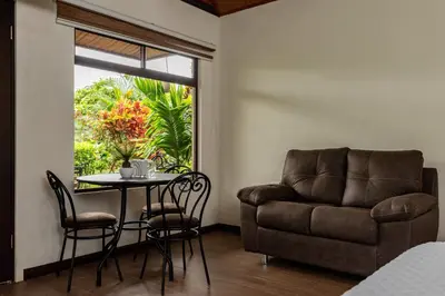 a living room with a chair and a table and a couch at Cabañas Acuarelas del Arenal in Fortuna