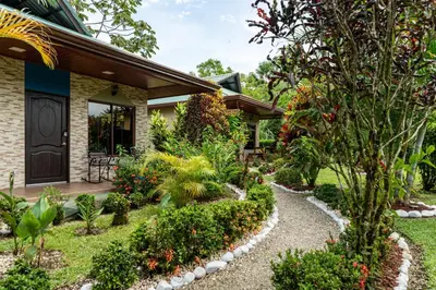 a garden in front of a house with plants at Cabañas Acuarelas del Arenal in Fortuna