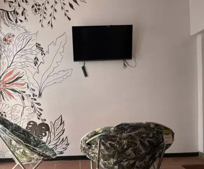 a flat screen tv hanging on a wall with a chair at Buganvilla Quepos Dos in Tapantí
