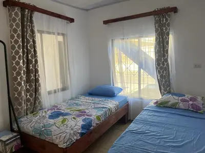 a bedroom with two beds and a window at Buganvilla Quepos Dos in Tapantí