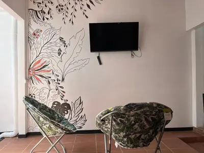 a flat screen tv hanging on a wall with two chairs at Buganvilla Quepos Dos in Tapantí