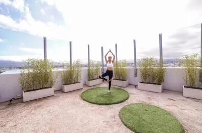 a woman doing yoga on the roof of a building at Luxury 12th Floor Apartment with Views - Downtown San Jose Pool and Gym in San José