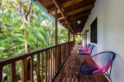 two chairs sitting on a porch with trees at The Sunset Shack in Nosara