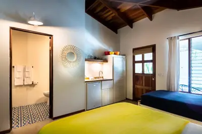 a bedroom with a bed and a small bathroom at The Sunset Shack in Nosara