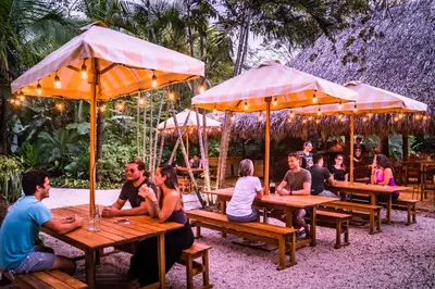 a group of people sitting at tables under umbrellas at The Sunset Shack in Nosara