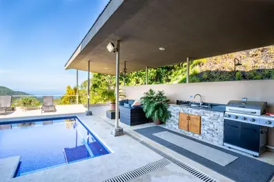 an outdoor kitchen and a swimming pool in a house at Villa Cielo in Jacó