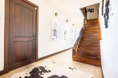 a hallway with a wooden door and a staircase at Villa Cielo in Jacó