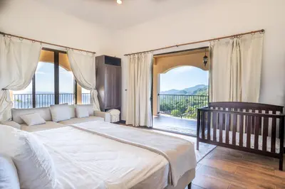 a bedroom with a large bed and a balcony at Villa Cielo in Jacó
