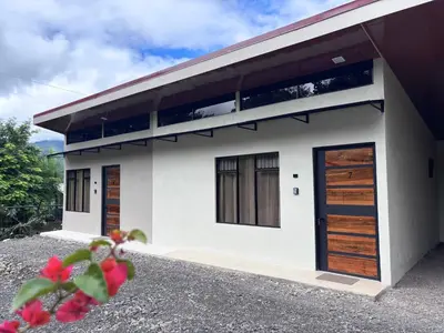 a white house with wooden doors and windows at Cabinas Las Veraneras - Dota in Santa María