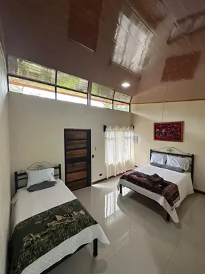 a bedroom with two beds and two windows at Cabinas Las Veraneras - Dota in Santa María