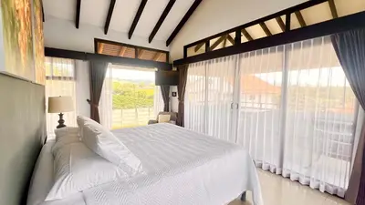a bedroom with a white bed and large windows at Ruta Verde BB in Tambor