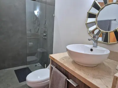 a bathroom with a sink and a toilet and a mirror at CasaMar 2BD & 2BA in Jacó