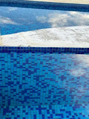 a blue tiled swimming pool with a reflection in the water at Hermosa Heights Villa 58 in Playa Hermosa