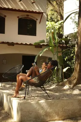 two women sitting in lawn chairs reading a book at Believe Surf & Yoga Lodge Santa Teresa in Santa Teresa Beach