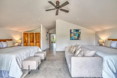 a bedroom with two beds and a couch and a ceiling fan at Blue Jungle Lodge in Arenal