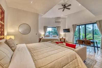 a bedroom with a large bed and a living room at Blue Jungle Lodge in Arenal
