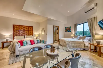 a bedroom with a king sized bed and a living room at Blue Jungle Lodge in Arenal