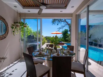 a dining room with a table and a pool at Casa White#2 Beautiful modern beach house in Sámara