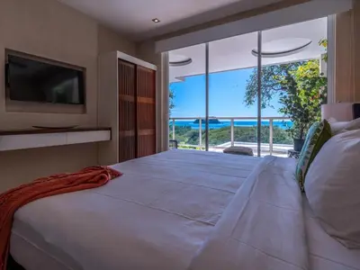a bedroom with a large bed with a view of the ocean at Casa White#2 Beautiful modern beach house in Sámara