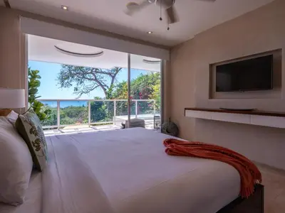 a bedroom with a large bed with a large window at Casa White Duplex Beautiful beach houses in Sámara