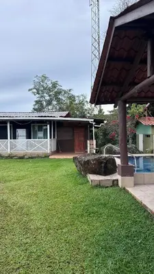 a house with a grass yard with a house at Quinta La Lomita in Turrialba