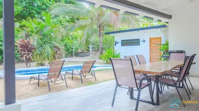 a table and chairs in a patio with a pool at Casa Encanto Charming house 5 minutes walking from the beach in Sámara