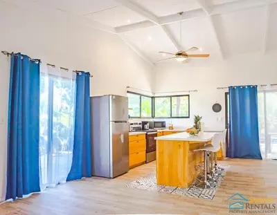 a kitchen with blue drapes and a table at Casa Encanto Charming house 5 minutes walking from the beach in Sámara