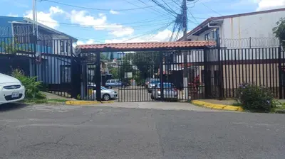 a black iron gate with cars parked behind it at Casa Amiga in San José