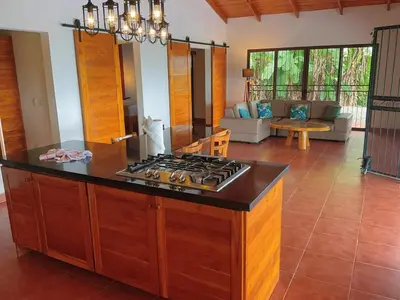 a kitchen with a stove and a living room at Casa Nekori Wonderful Mountain view 15 minutes from Samara in Nicoya