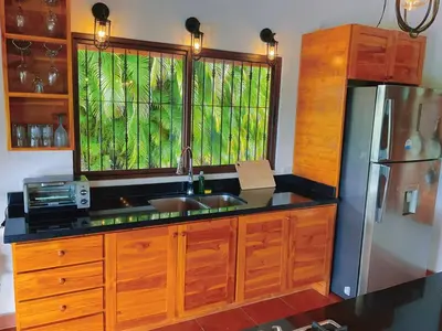a kitchen with a sink and a refrigerator at Casa Nekori Wonderful Mountain view 15 minutes from Samara in Nicoya