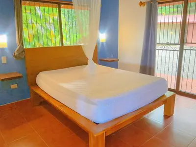 a large bed in a room with windows at Casa Nekori Wonderful Mountain view 15 minutes from Samara in Nicoya