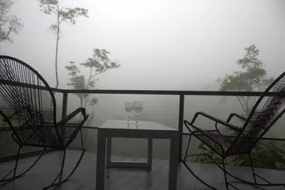 two chairs and a table with two wine glasses on a balcony at Village Río Celeste, Eco Lodge and Tours in Rio Celeste
