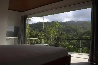 a bedroom with a large window with a mountain view at Village Río Celeste, Eco Lodge and Tours in Rio Celeste