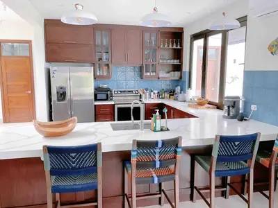 a kitchen with a large island with chairs in it at Villa Hermanos Luxury Home with Ocean View in Sámara