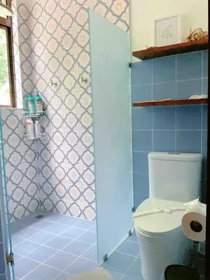 a bathroom with a toilet and a shower with blue tiles at Villa Hermanos Luxury Home with Ocean View in Sámara