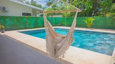 a hammock in front of a swimming pool at Casa Jurassic Amazing villa 10 min walk to the beach in Sámara