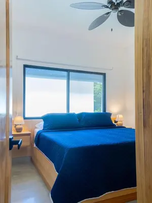 a bedroom with a blue bed and a large window at Casa Jurassic Amazing villa 10 min walk to the beach in Sámara