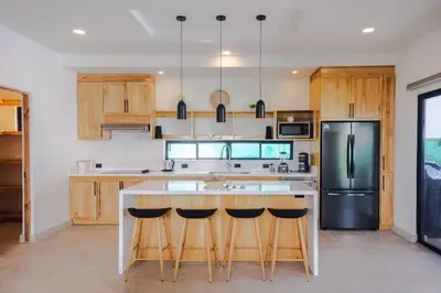 a kitchen with a island with bar stools and a refrigerator at Casa Jurassic Amazing villa 10 min walk to the beach in Sámara