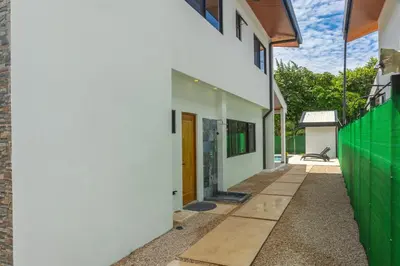 a white house with a green fence at Casa Cretaceous Modern villa 10 min walk to the beach in Sámara